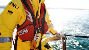 An RNLI crew member onboard a lifeboat wearing their red lifejacket