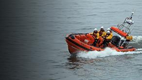 Stonehaven Lifeboat Station’s B class lifeboat is powering through the water at sea with four crew members onboard.
