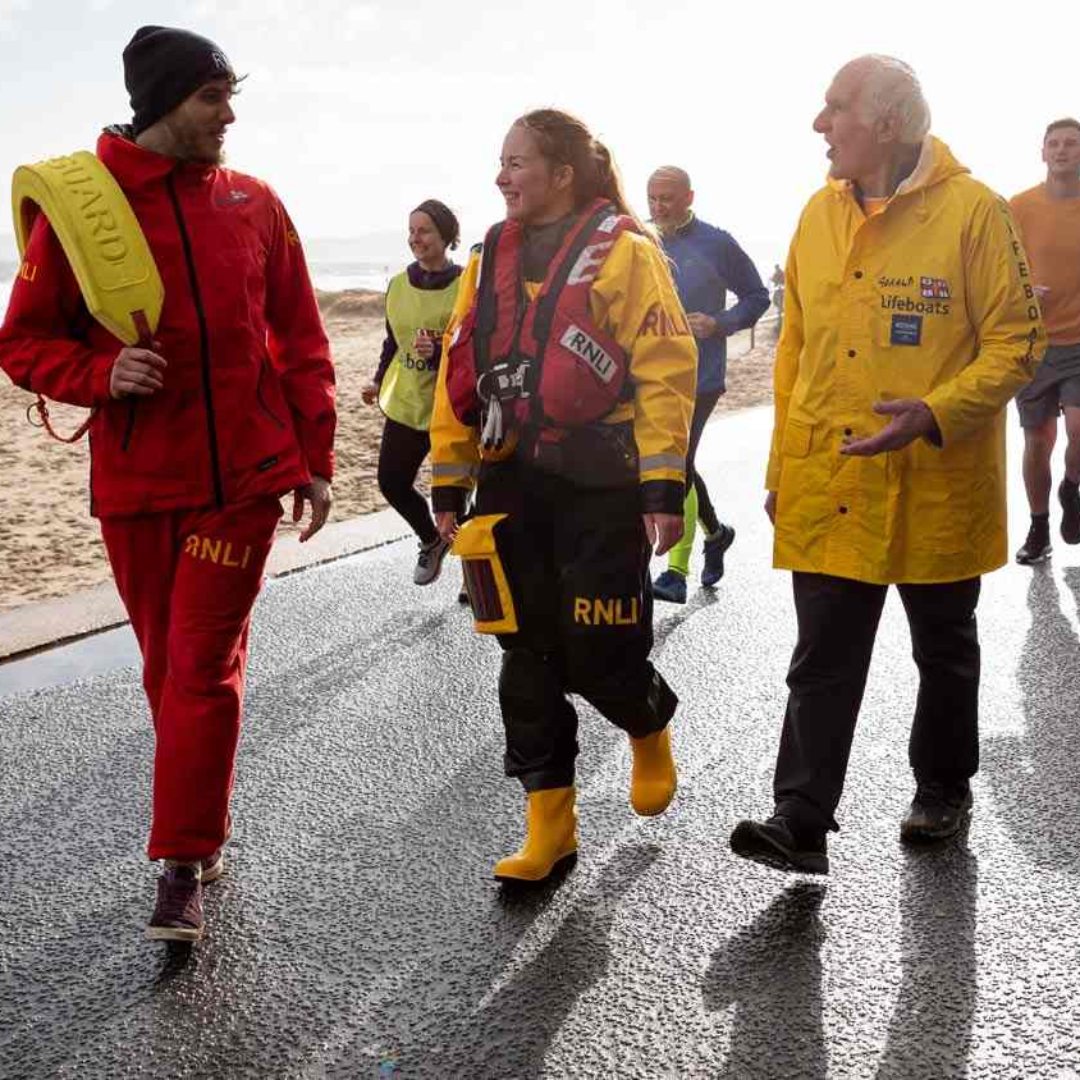 RNLI fundraisers on the beach, a lifeguard, a crew member and a fundraiser in a yellow coat