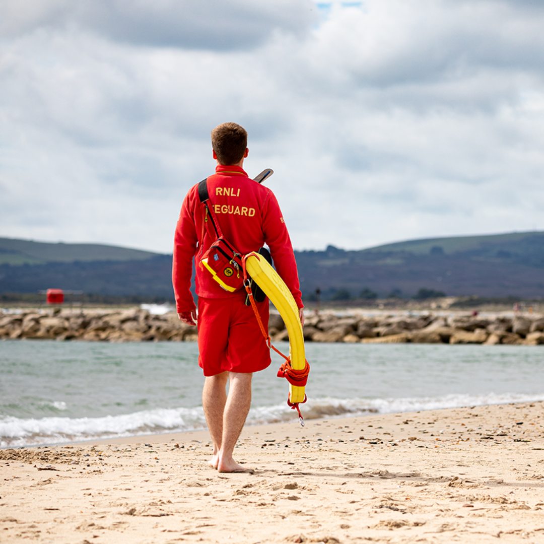 RNLI lifeguard patrolling the waters edge on a beach