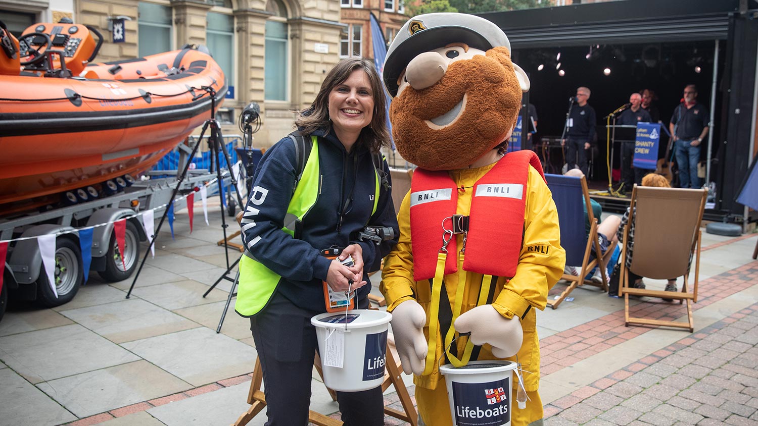 An RNLI fundraiser standing next to Stormy Stan, an RNLI mascot