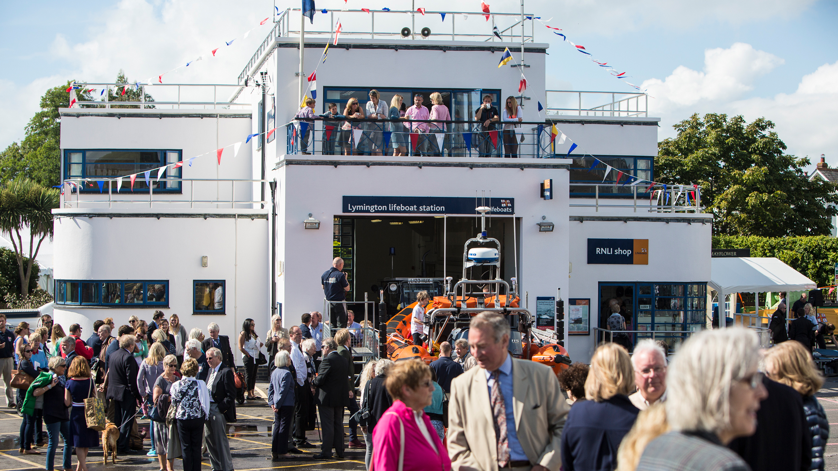 There are crowds of people in and around Lymington Lifeboat Station on a bright, sunny day.