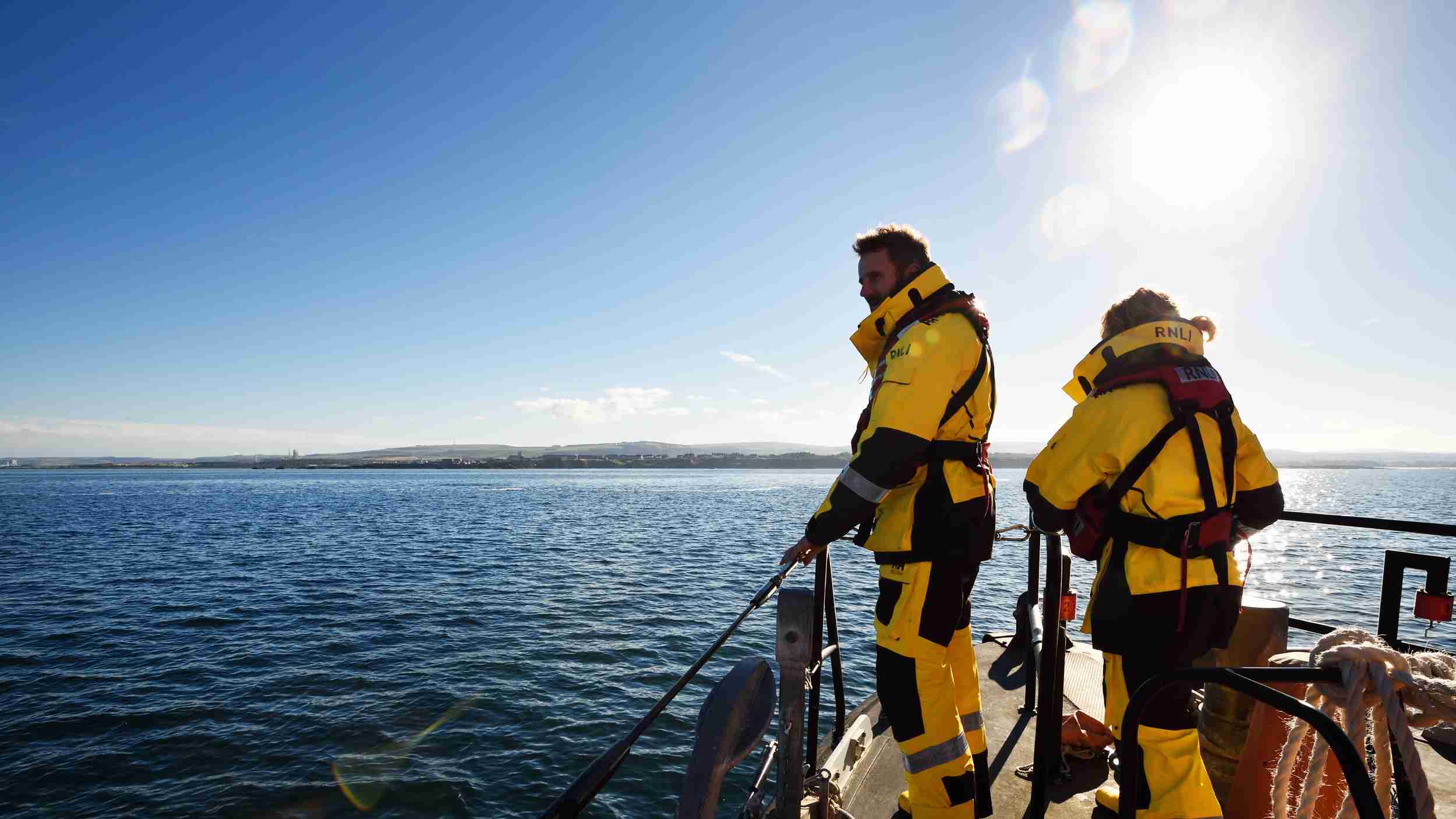 Dunbar crew members onboard the Trent class lifeboat John Neville Taylor 14-35 at sea. Sunny day with blue sky.
