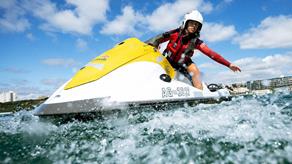 Female lifeguard on rescue watercraft reaches out into the water