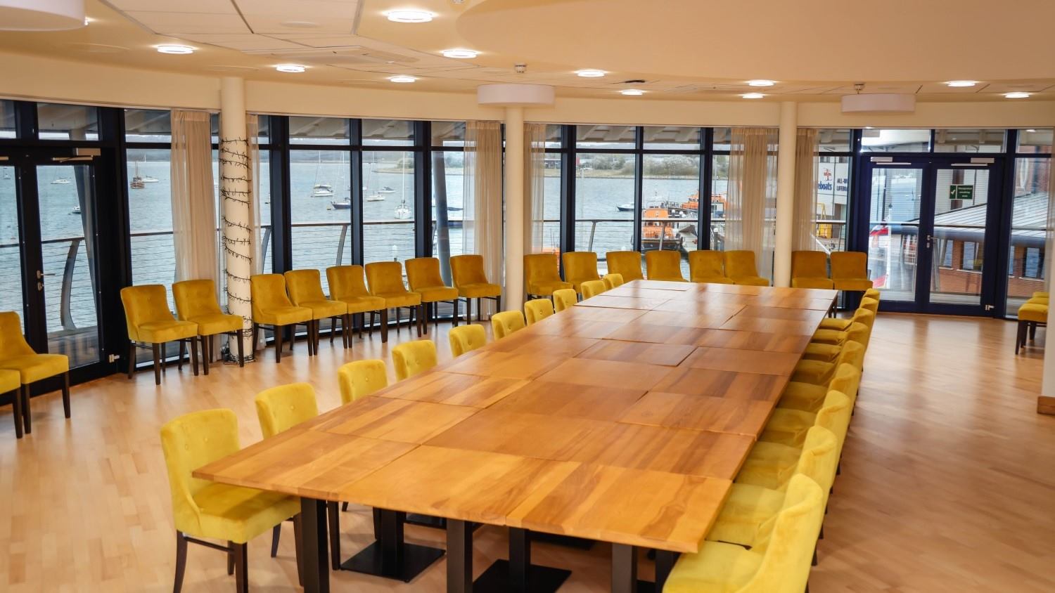 Harbour View room set up with large boardroom style table, view of the harbour through the floor to ceiling windows