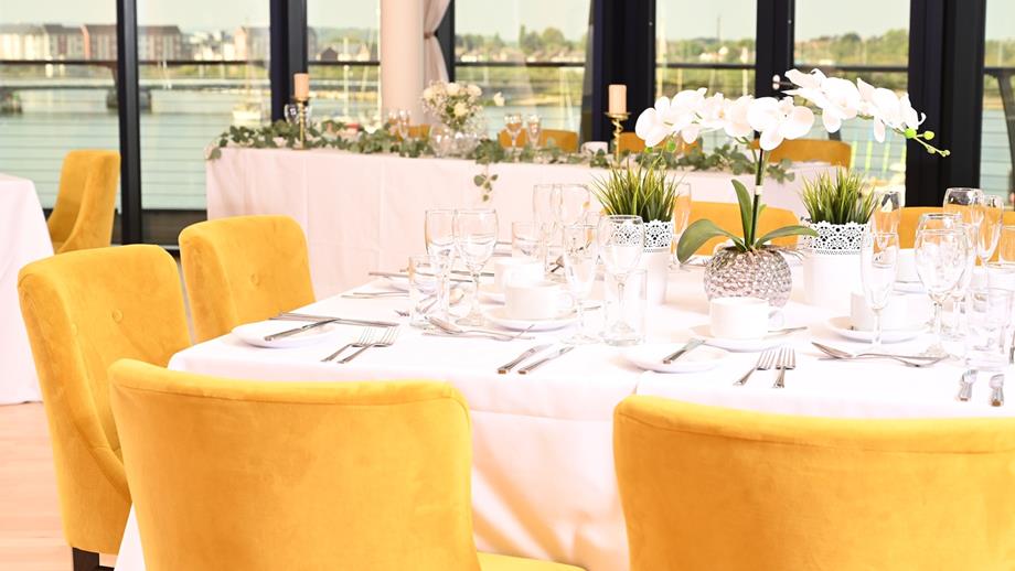 Dressed tables and chairs in the Harbour View Suite at the RNLI College, ready for an evening wedding celebration.
