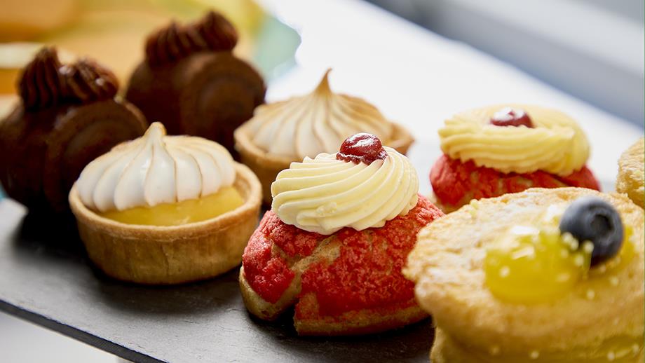 A selection of delicious cakes on a black slate serving dish.